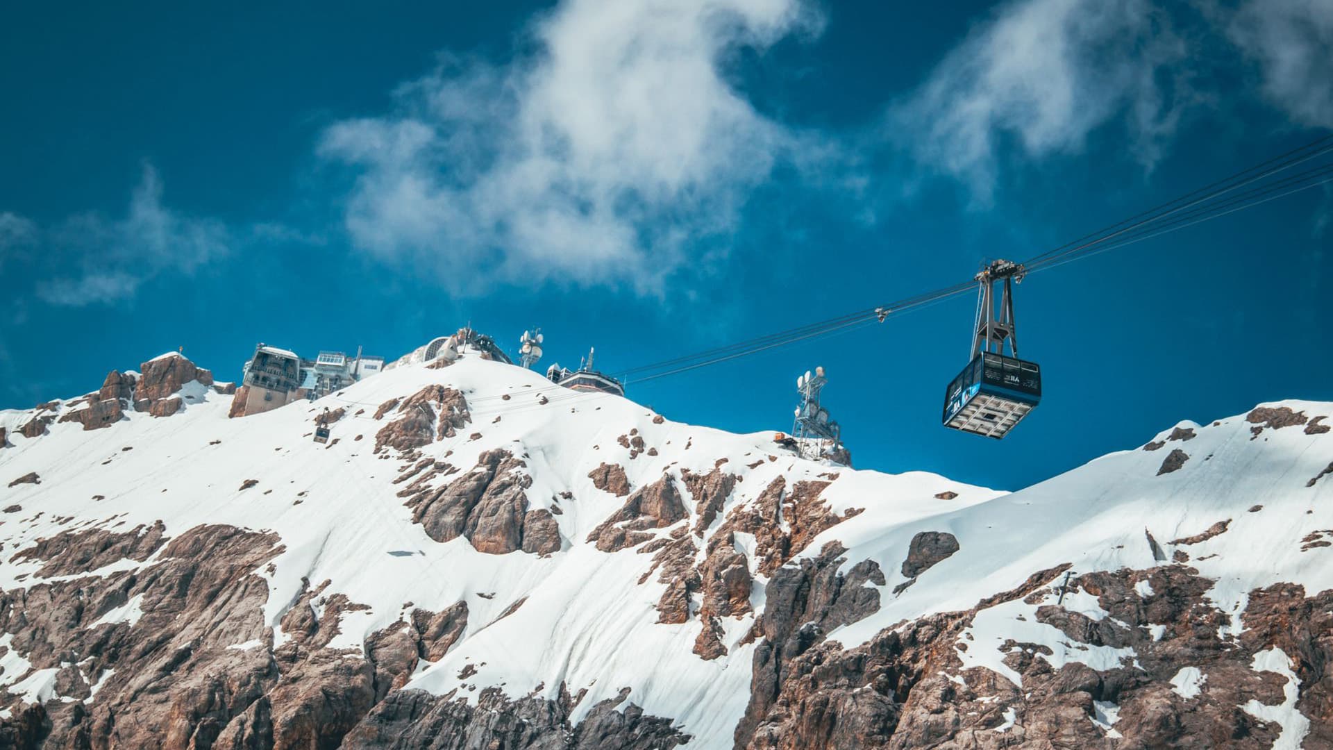 Cable car ascending toward a snow-covered alpine peak in the Swiss Alps